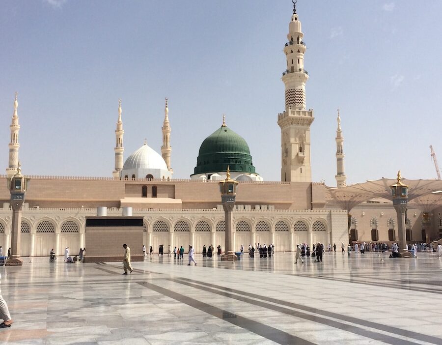 people walking outside a dome mosque building