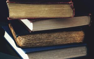 Close-up of a stack of vintage books with worn bindings, showcasing aged paper and textures.