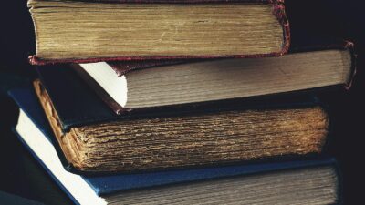 Close-up of a stack of vintage books with worn bindings, showcasing aged paper and textures.