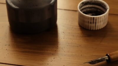 Elegant still life of an ink bottle and dipping pens on a wooden table.