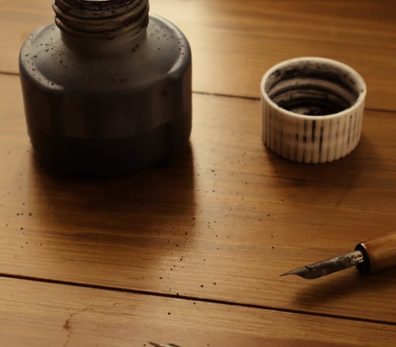 Elegant still life of an ink bottle and dipping pens on a wooden table.