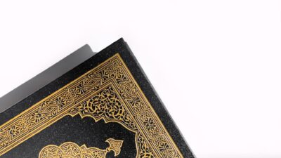 A beautifully detailed Quran cover with golden patterns on a white background, symbolizing spirituality.